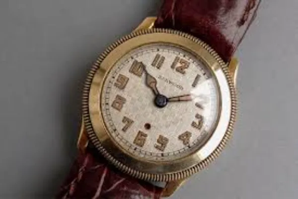 Close-up of a vintage gold-toned automatic wristwatch with a textured dial and bold numerals, on a brown leather strap.