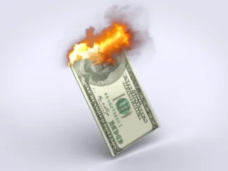 Burning US dollar bill symbolizing inflation eroding purchasing power and causing financial stress.